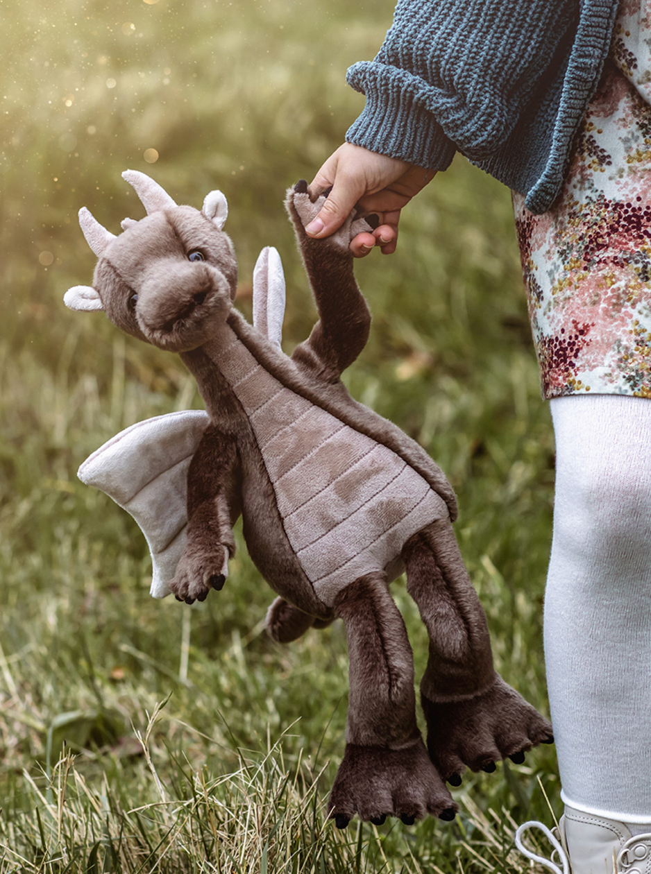 Plush dragon toy held by a person outdoors