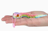 Colorful toy lizard on a person's hand against a white background